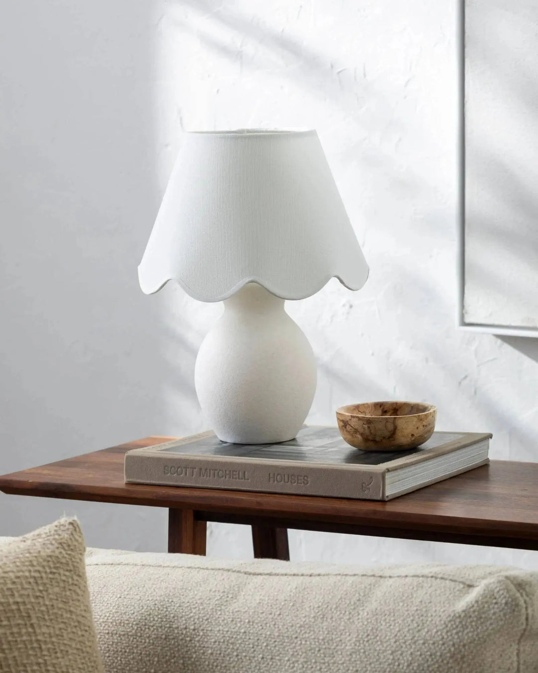 Lampe de table DOLCE blanche sur des livres près d’un canapé