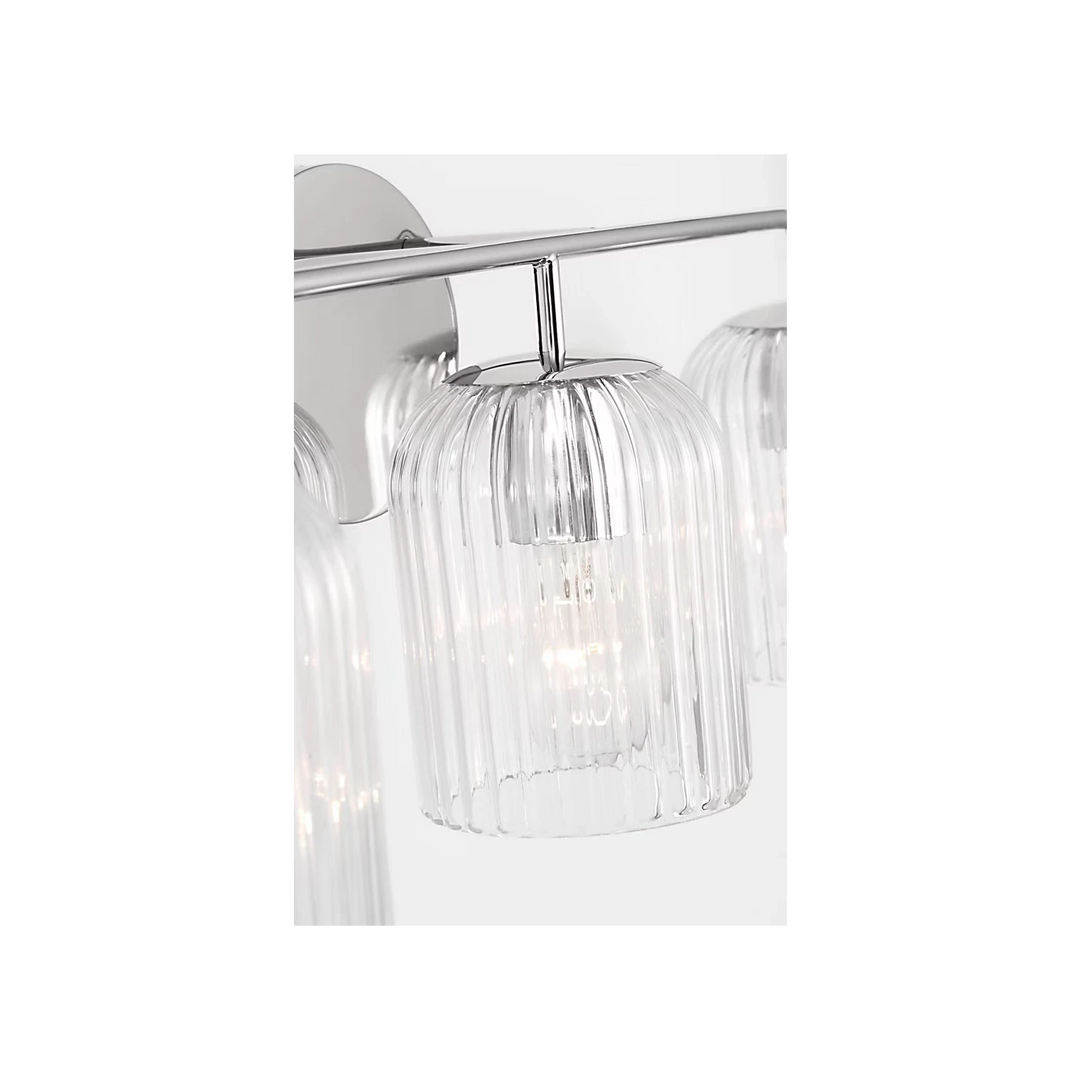 Maison Olive applique murale avec trois abat-jours cylindriques en verre strié transparent et finition laiton brossé.