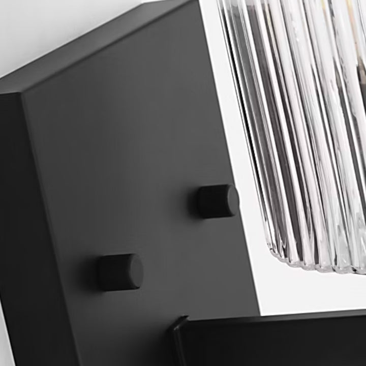 Maison Olive applique murale moderne en métal noir brossé avec abat-jour cylindrique en verre strié transparent.