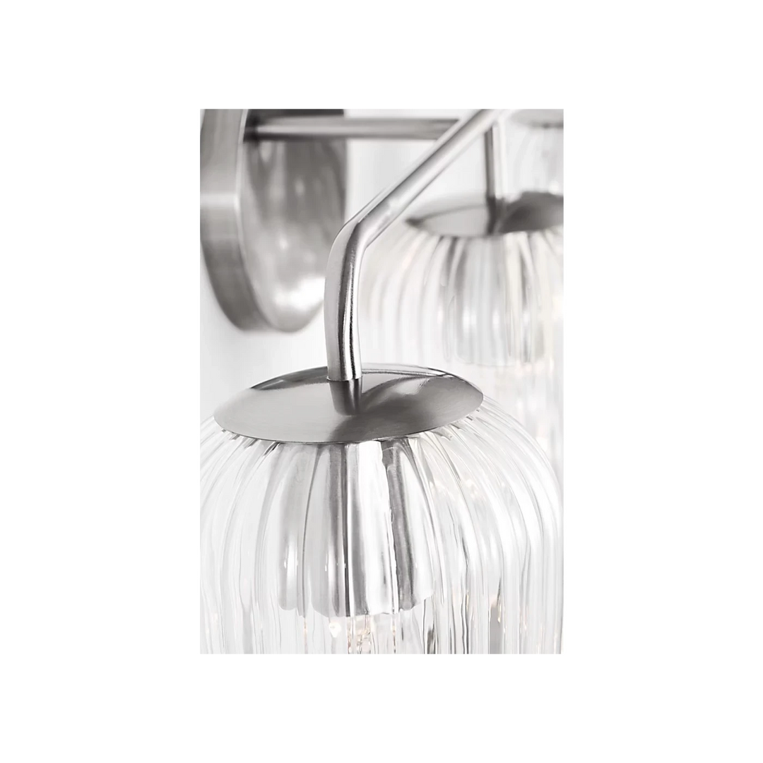 Applique murale Maison Olive en métal argenté avec 3 globes en verre strié transparent diffusant une lumière douce.