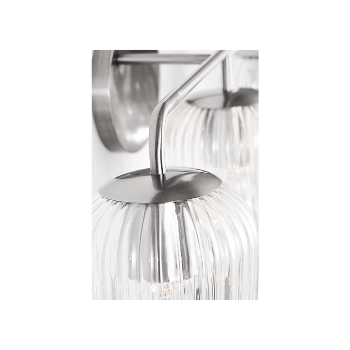 Applique murale Maison Olive en métal argenté avec 3 globes en verre strié transparent diffusant une lumière douce.