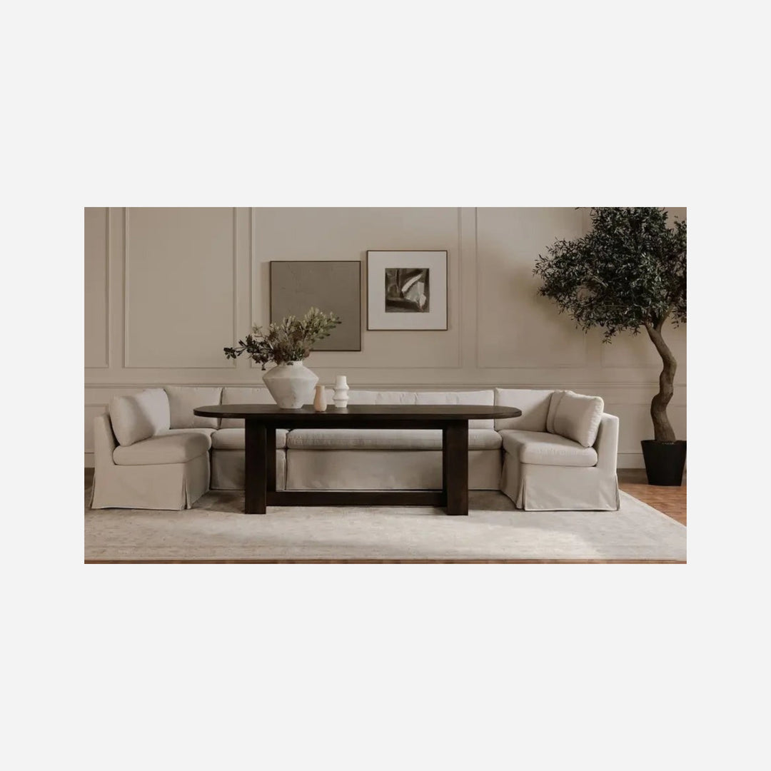 Banquette de salle à manger Maison Olive FABLE en tissu beige texturé avec jupe, installée autour d'une table sombre.