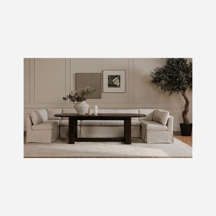 Banquette de salle à manger Maison Olive FABLE en tissu beige texturé avec jupe, installée autour d'une table sombre.
