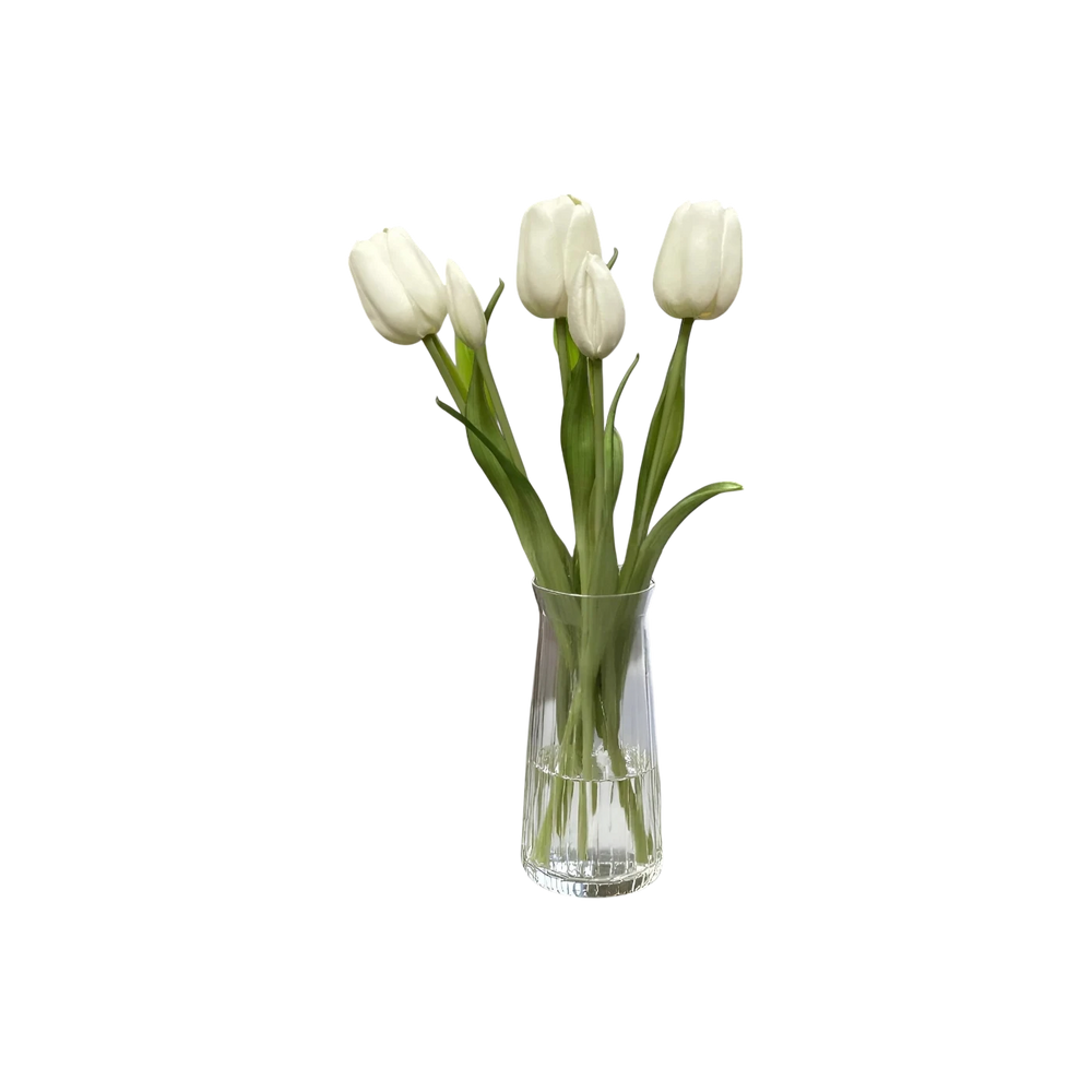 Bouquet de tulipes artificielles blanches dans un vase en verre transparent sur un socle en marbre. Décoration intérieure.