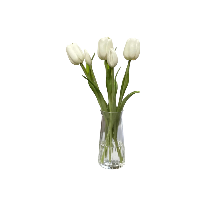 Bouquet de tulipes artificielles blanches dans un vase en verre transparent sur un socle en marbre. Décoration intérieure.