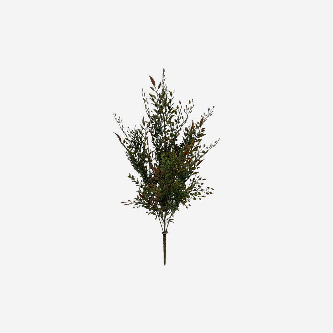 Branche artificielle Maison Olive avec feuillage vert et pointes cuivrées sur fond de mur en briques grises