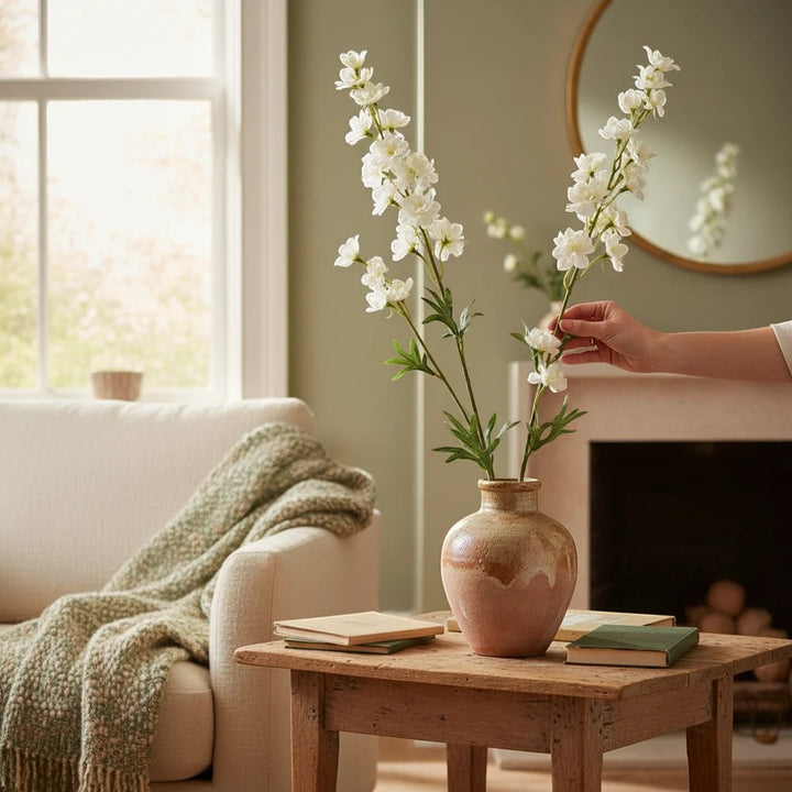 Maison Olive Branche de delphinium artificielle blanc avec de multiples petites fleurs dans un vase en terre cuite.