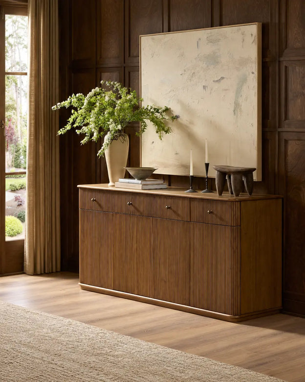 Buffet en bois cannelé présenté en entier avec vase fleuri et œuvre abstraite
