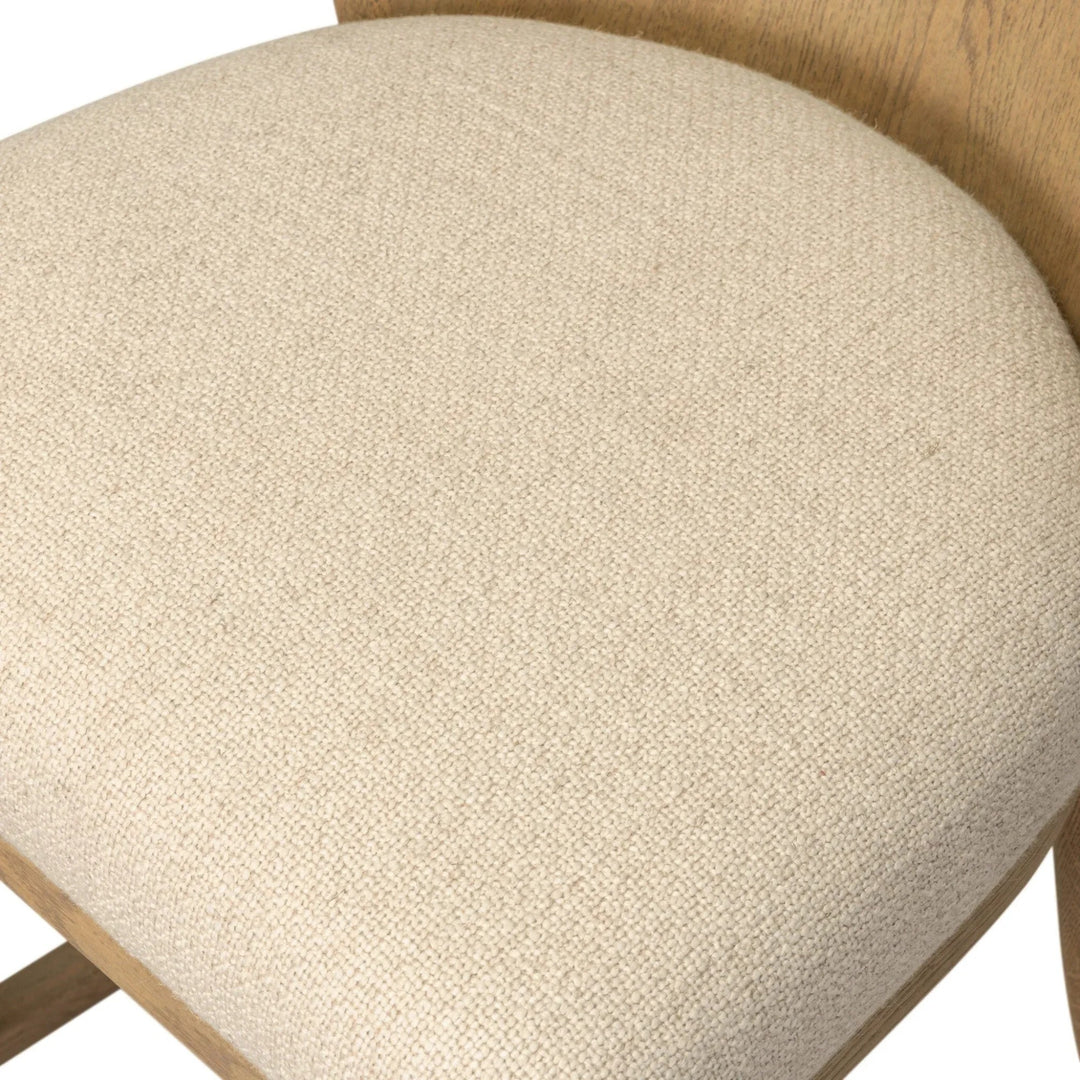 Maison Olive Chaise en bois clair avec assise rembourrée en tissu crème texturé. Design épuré et naturel.