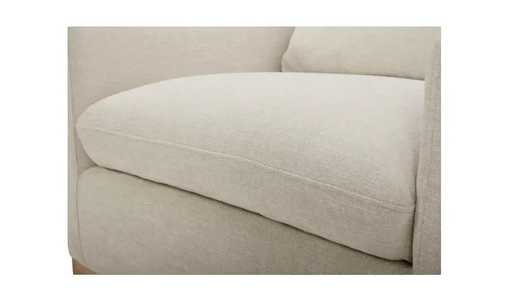 Gros plan sur l'assise en tissu texturé taupe du fauteuil pivotant contemporain Maison Olive avec base en bois clair.