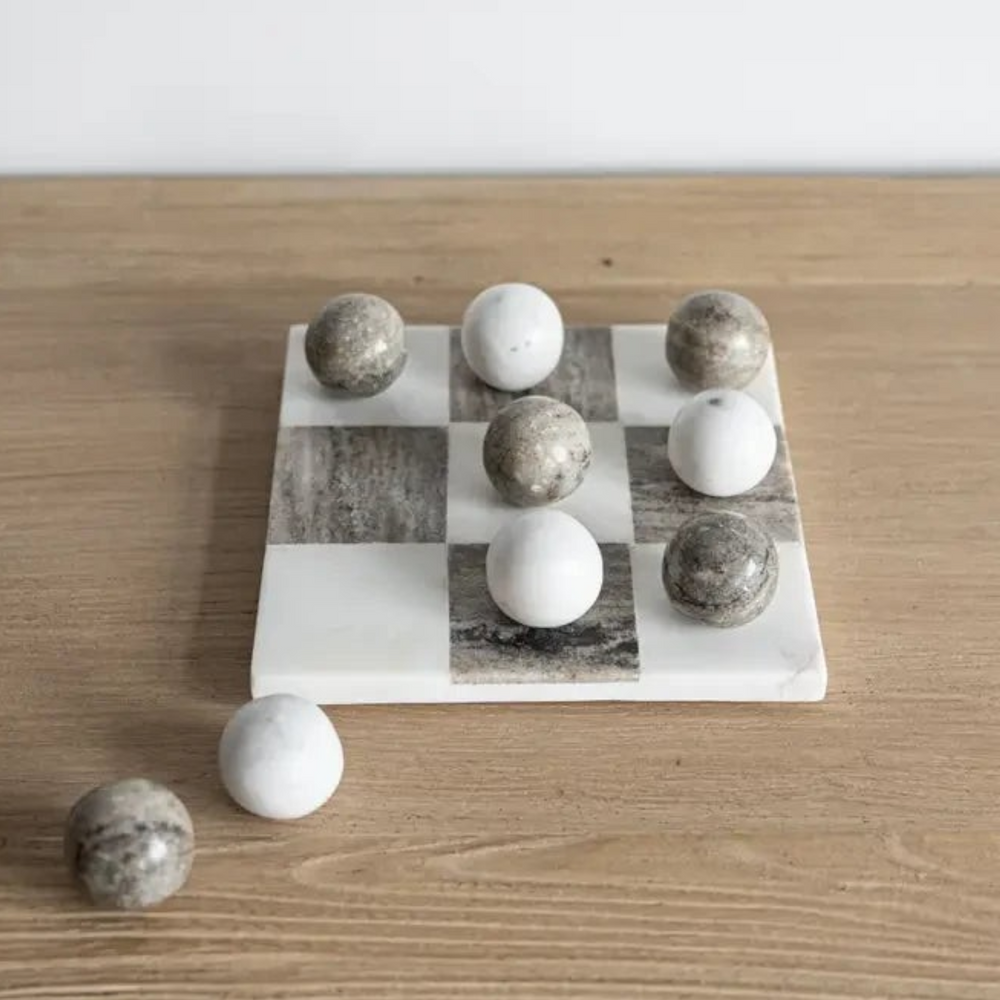 Jeu de morpion Maison Olive en marbre blanc et gris avec pions sphériques polis sur un plateau carré en pierre