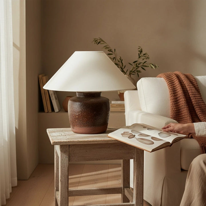 Lampe de table Maison Olive en céramique brune texturée avec abat-jour blanc sur une table en bois rustique