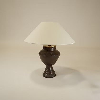 Lampe de table Maison Olive en céramique sombre texturée avec détails en laiton doré et abat-jour en tissu clair.