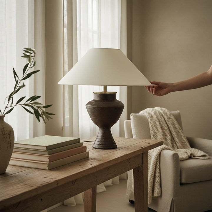 Lampe de table Maison Olive en céramique sombre texturée avec abat-jour en tissu clair et détails en laiton doré.