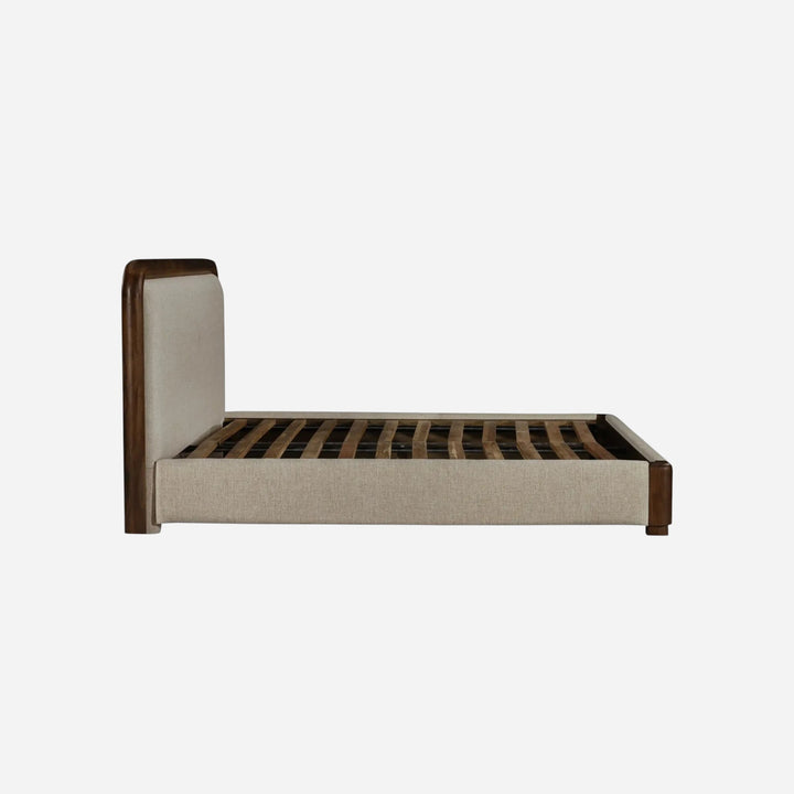 Lit Maison Olive avec cadre en bois massif sombre et tête de lit rembourrée en tissu beige, vue de profil
