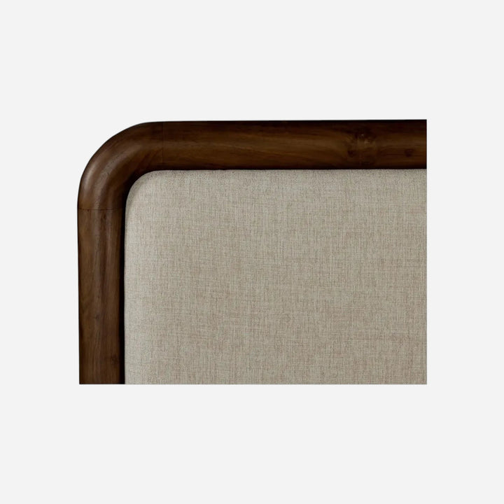 Gros plan sur l'angle arrondi d'un lit Maison Olive avec cadre en bois massif sombre et tissu texturé beige