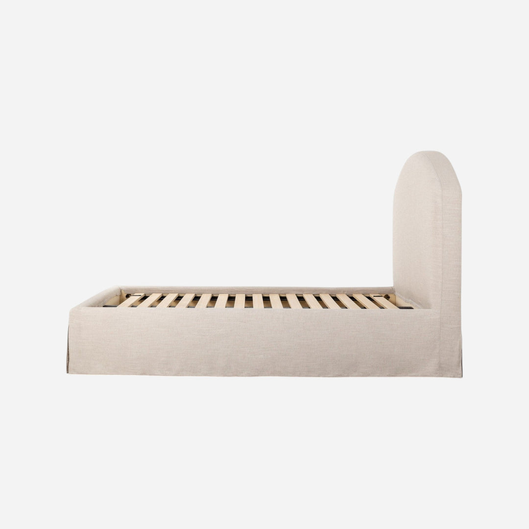 Lit Maison Olive en tissu texturé crème avec jupe et tête de lit arquée, sommier à lattes inclus.
