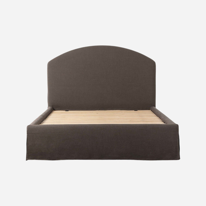 Lit capitonné Maison Olive avec jupe et tête de lit arquée en tissu texturé gris foncé, sommier à lattes inclus.