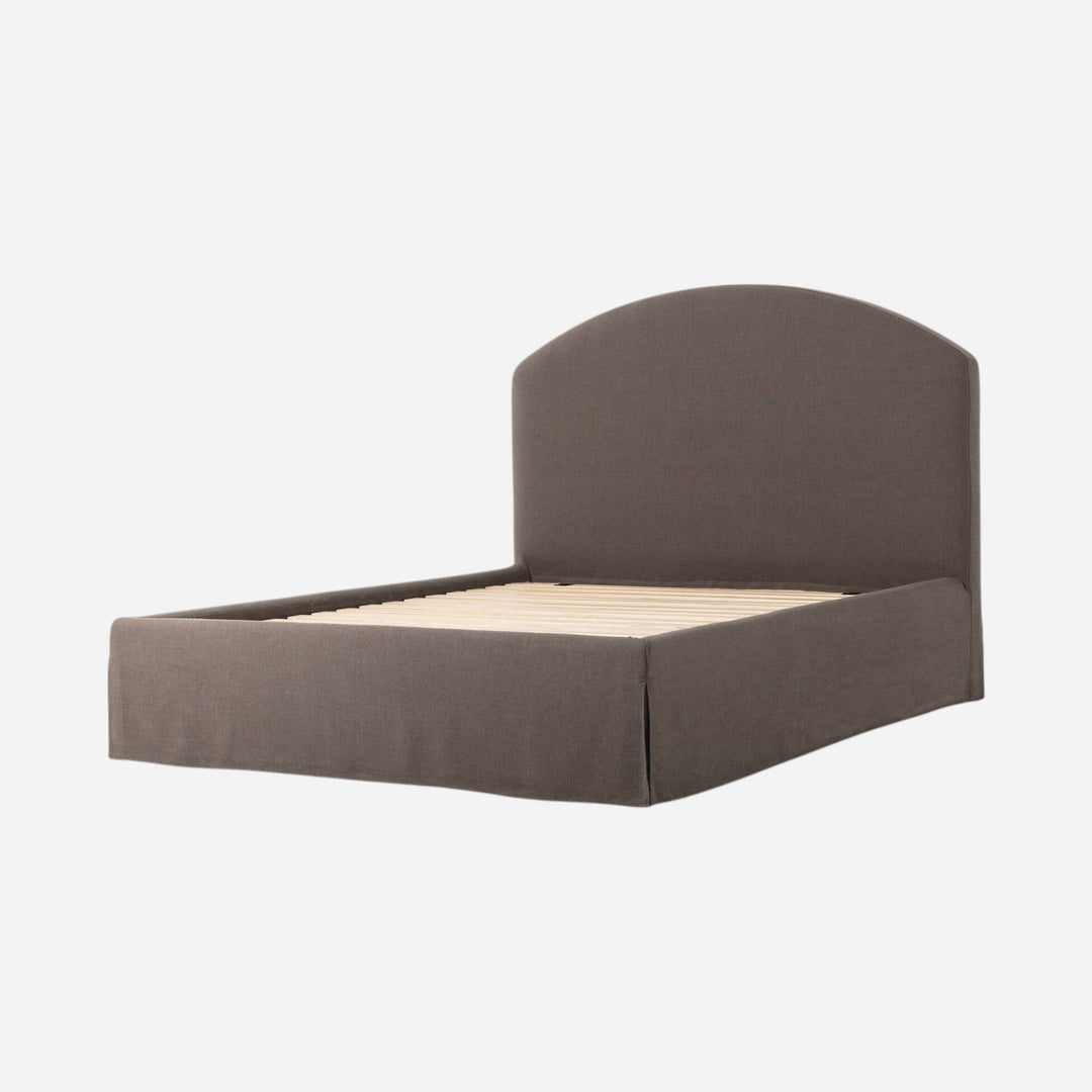 Lit capitonné Maison Olive avec jupe et tête de lit arquée en tissu texturé gris, sommier à lattes inclus.