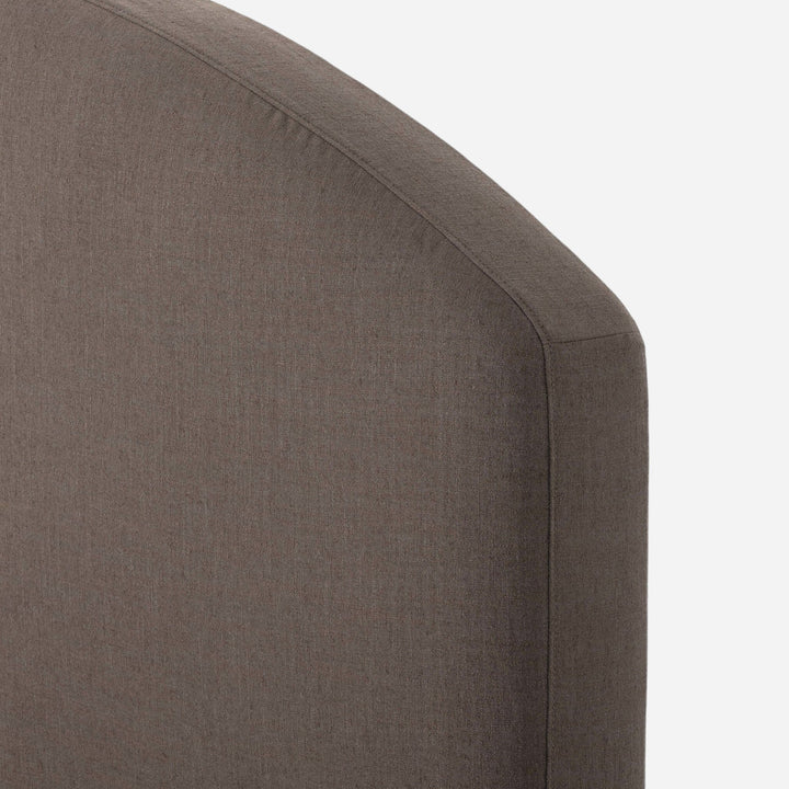 Lit capitonné Maison Olive avec tête de lit arquée en tissu texturé marron.