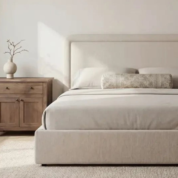 Lit coffre Maison Olive en tissu beige avec tête de lit arrondie et design minimaliste dans une chambre lumineuse