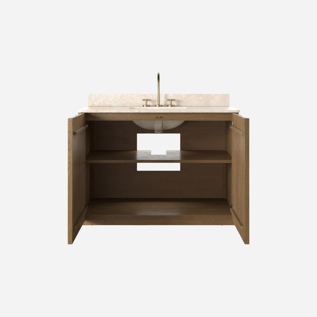 Maison Olive meuble de salle de bain suspendu en bois de chêne avec plateau en marbre crème et vasque blanche. Portes ouvertes sur étagères.