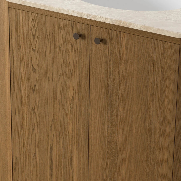 Meuble vasque Maison Olive en bois de chêne naturel avec plateau en pierre beige et poignées bronze. Design organique.