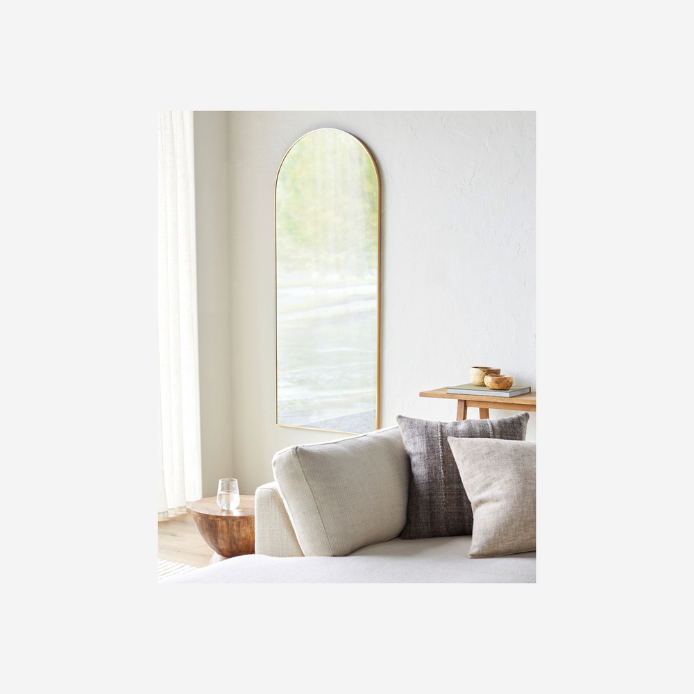 Miroir pleine longueur Maison Olive Aranya avec cadre fin doré et silhouette arquée dans un salon lumineux