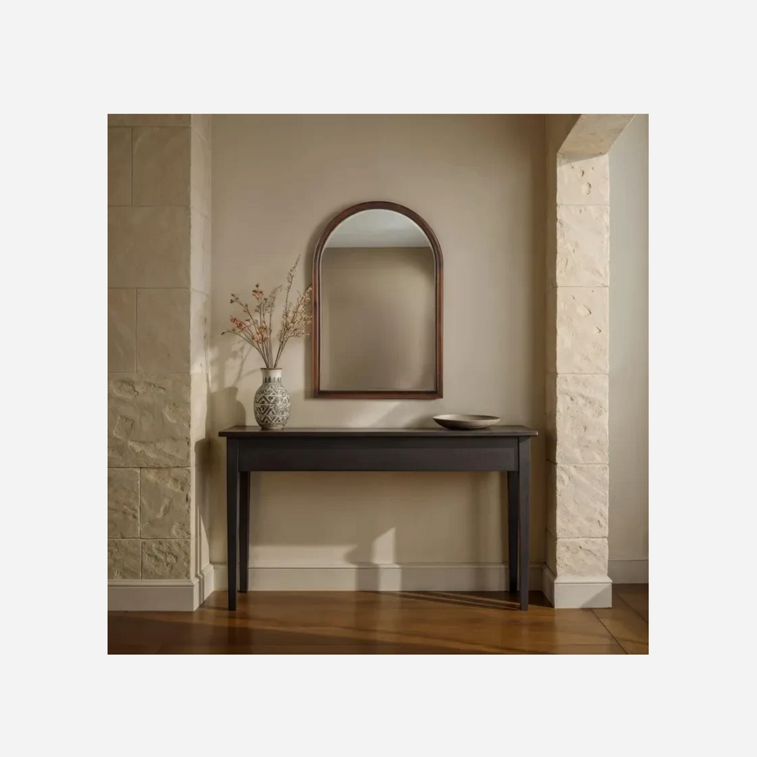 Miroir mural arqué Maison Olive avec cadre en bois finition noyer, suspendu au-dessus d'une console dans une entrée.