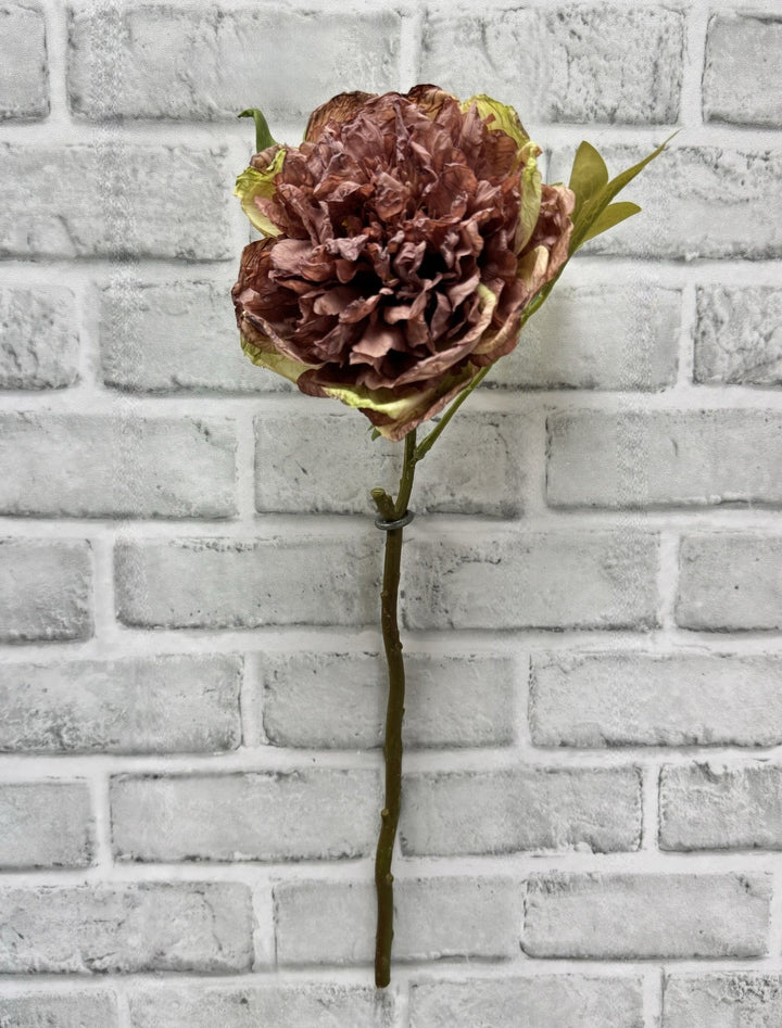 Pivoine artificielle Maison Olive vieux rose et brun avec pétales texturés sur fond de mur en briques grises