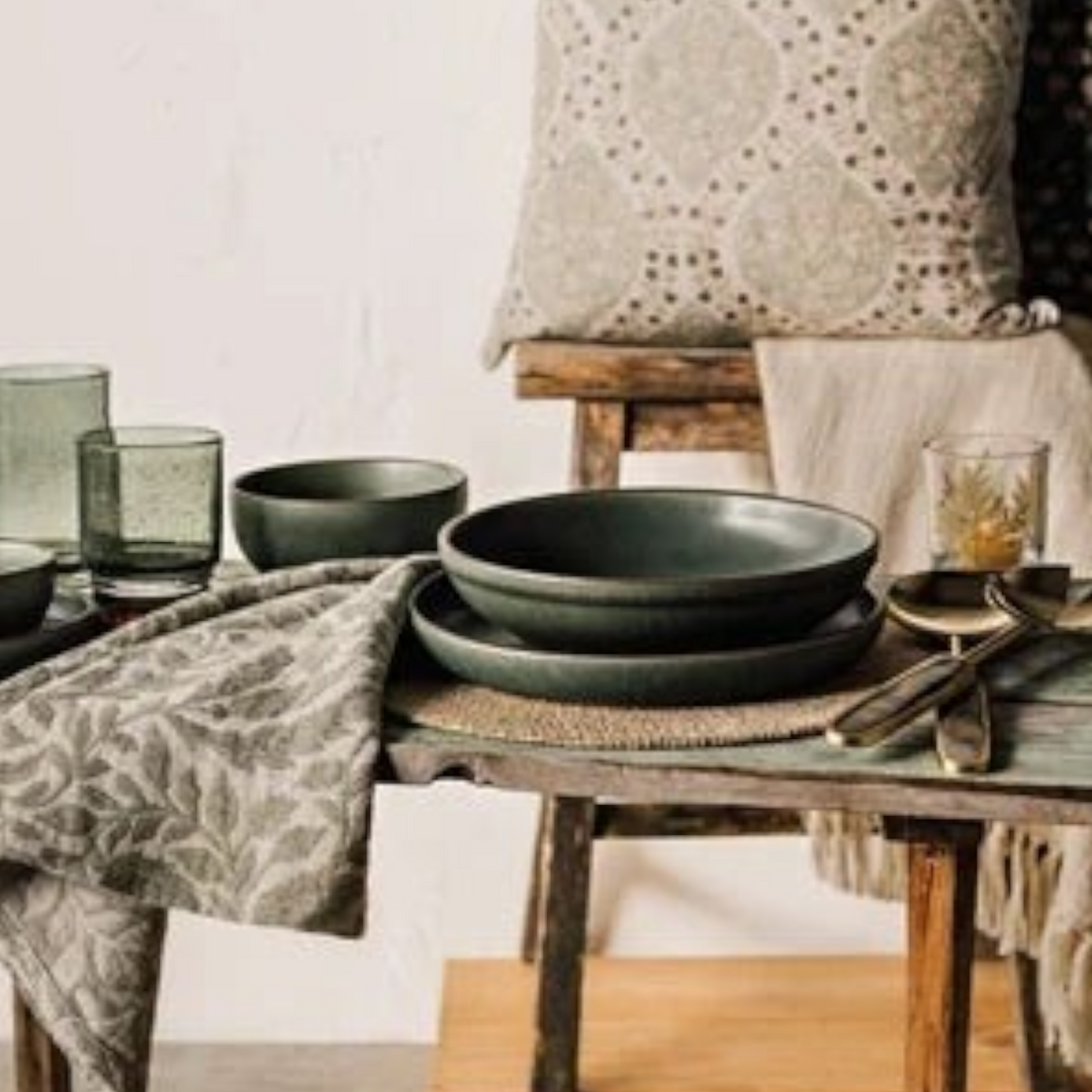 Serviette de table en coton Maison Olive à motif végétal gris posée sur une table rustique avec vaisselle en céramique