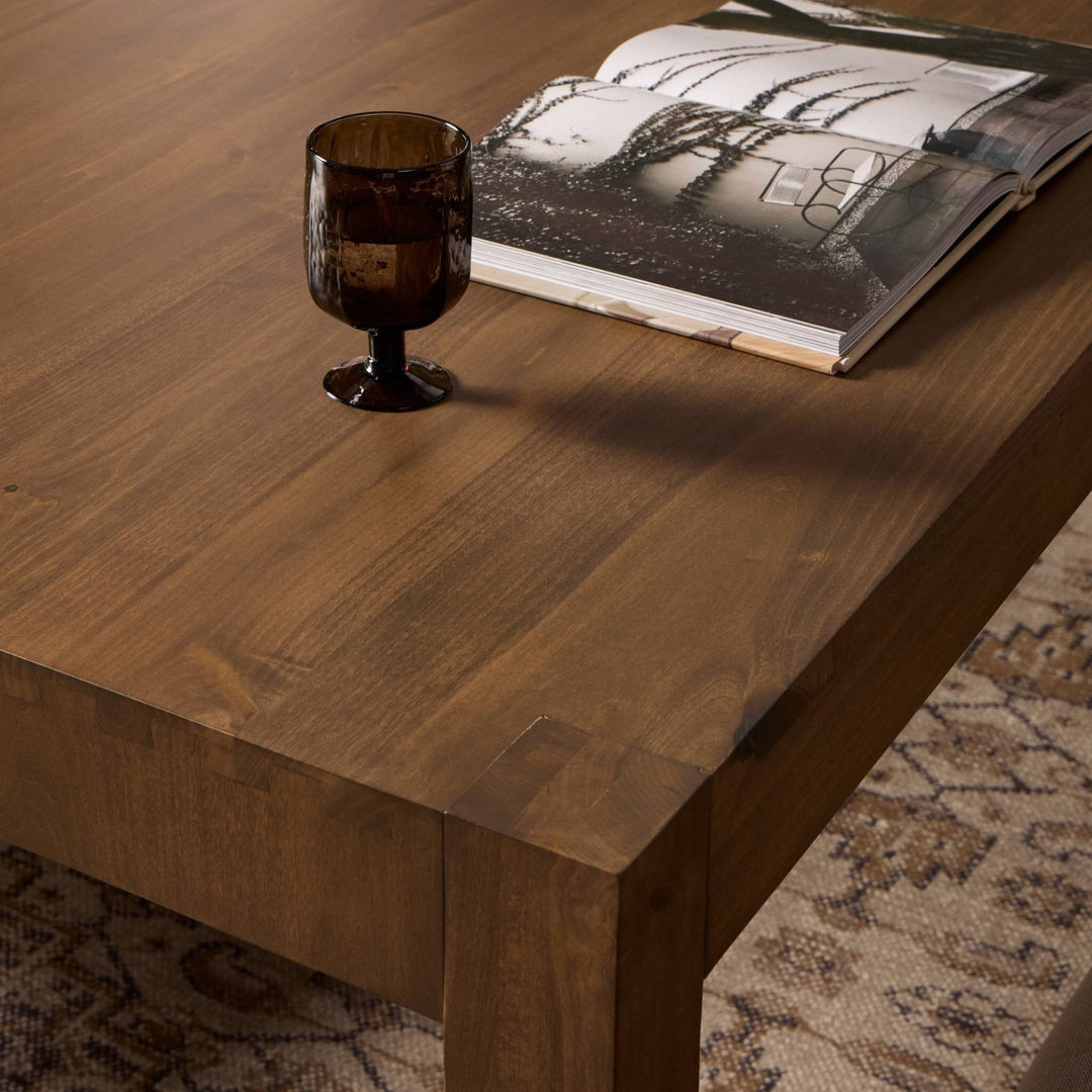 Maison Olive table basse contemporaine en bois massif brun avec un verre et un livre ouvert.