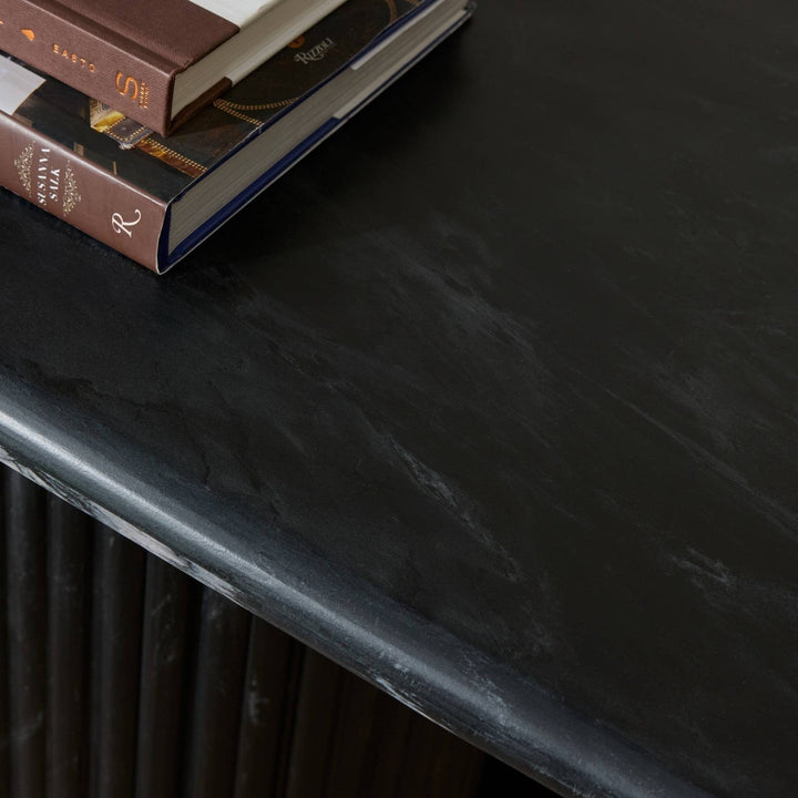 Maison Olive Table basse ovale en marbre noir veiné avec pied cannelé, design sculptural et élégant.