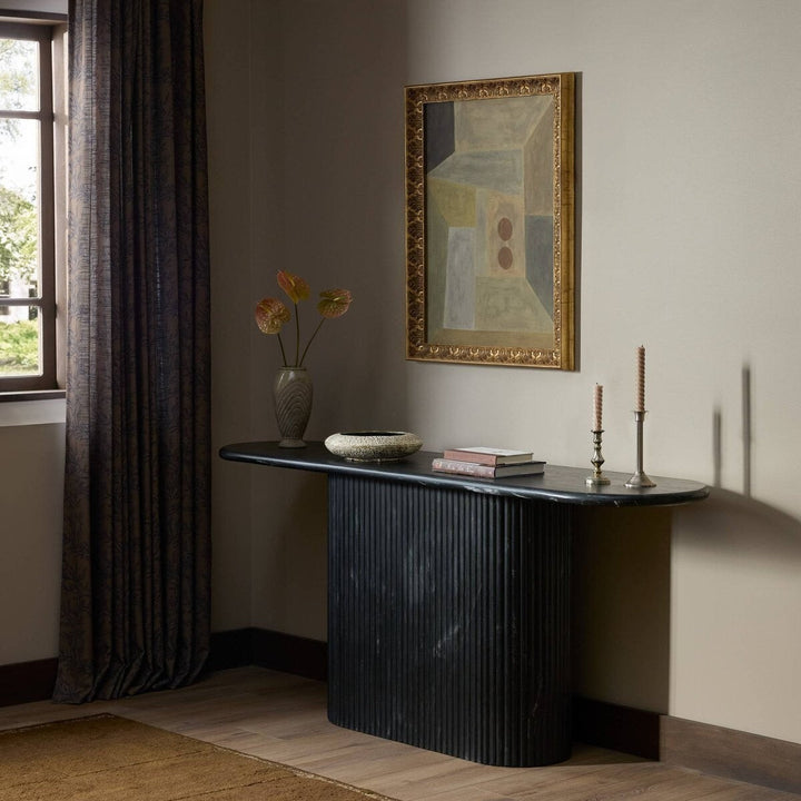 Maison Olive table basse ovale en marbre noir veiné avec pied cannelé, design sculptural et élégant.