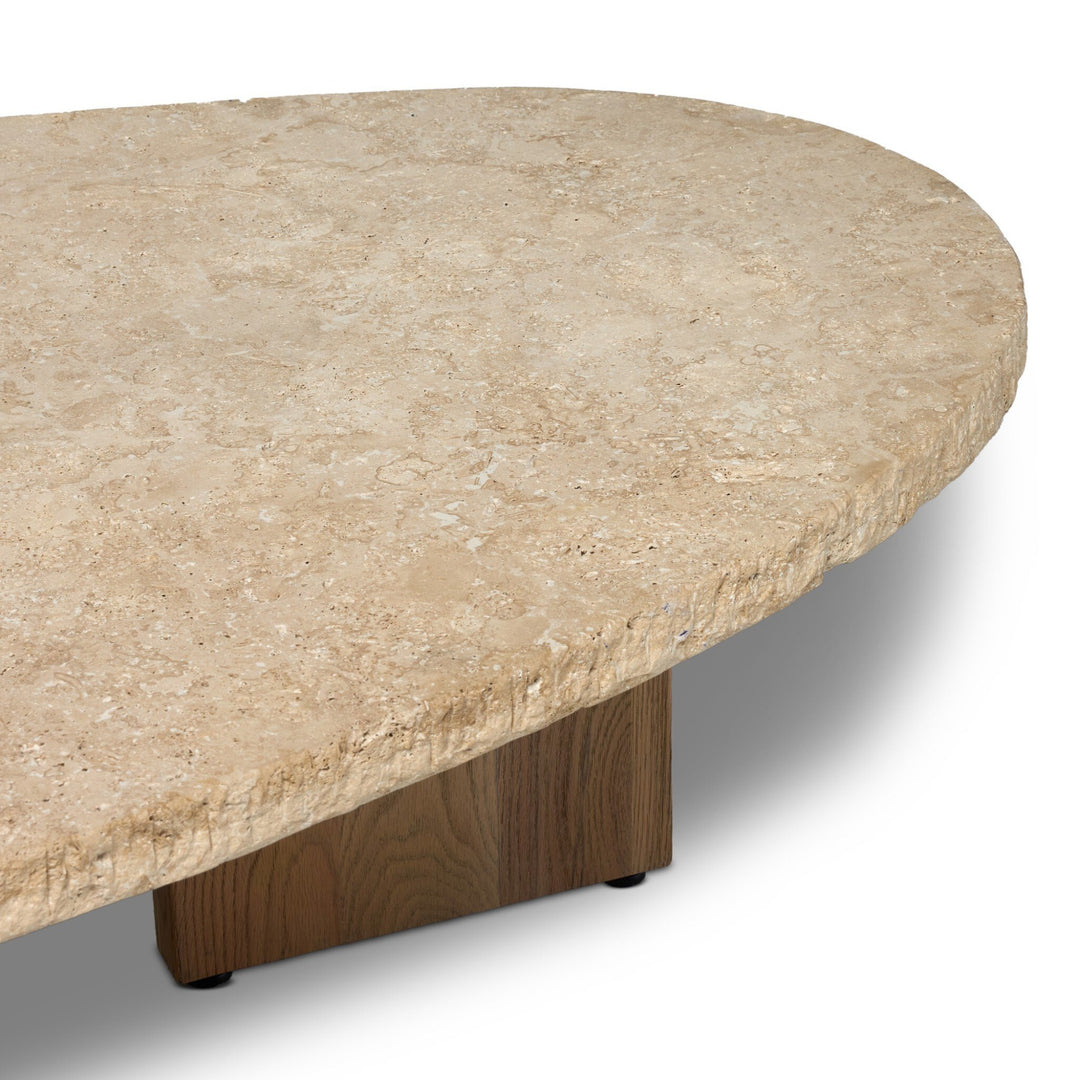 Table basse Maison Olive en travertin beige texturé aux bords bruts, avec un pied en bois massif.