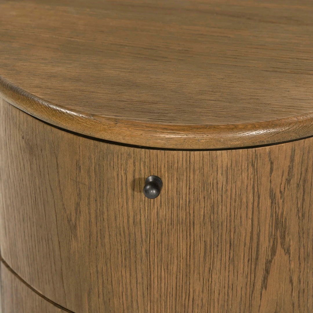 Maison Olive Table de chevet ronde en bois de chêne massif avec tiroir et poignée noire. Design cylindrique chaleureux.