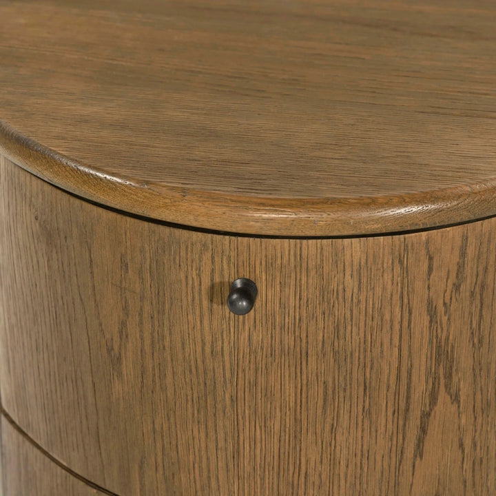Maison Olive Table de chevet ronde en bois de chêne massif avec tiroir et poignée noire. Design cylindrique chaleureux.