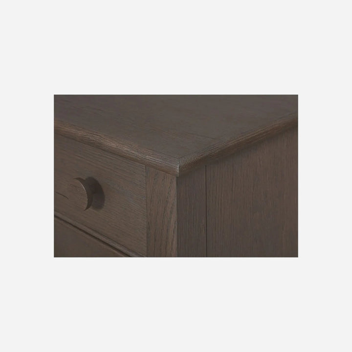 Gros plan sur le coin d'une table de chevet Maison Olive en bois massif sombre avec un tiroir et poignée ronde
