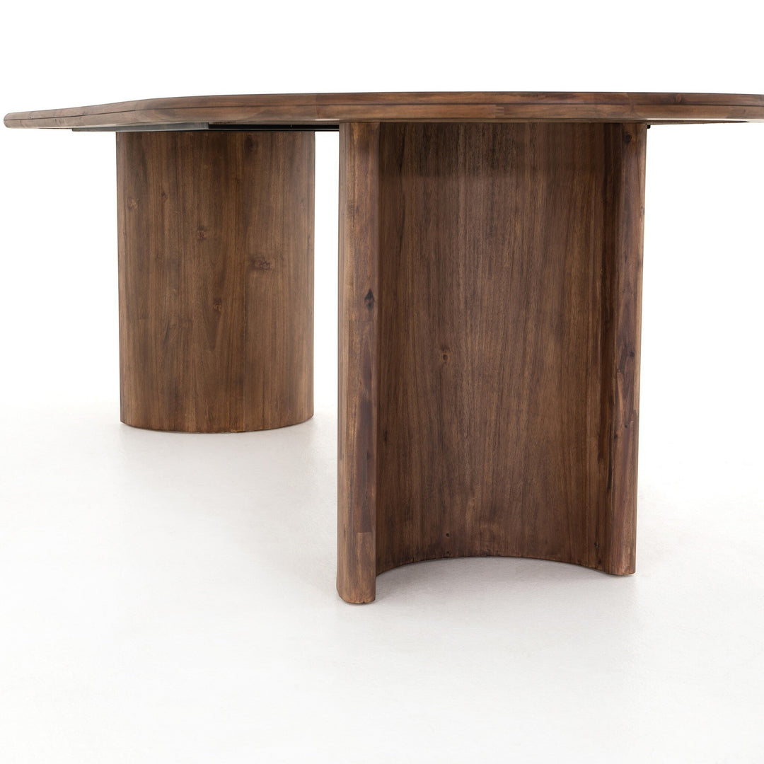 Table à manger ovale en bois d'acacia noir vieilli de Maison Olive, design sculptural avec piétement cylindrique.