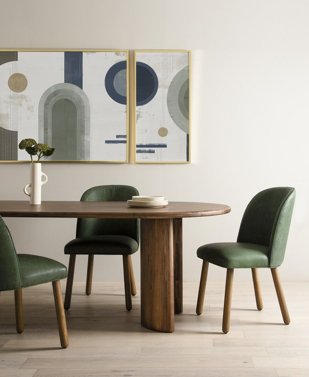 Maison Olive Table à manger ovale en bois d'acacia noir vieilli avec piétement cylindrique et chaises vertes.