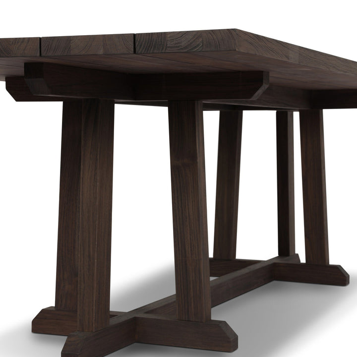 Table à manger Maison Olive en bois massif foncé, plateau à lattes, pieds croisés en H, style rustique moderne.