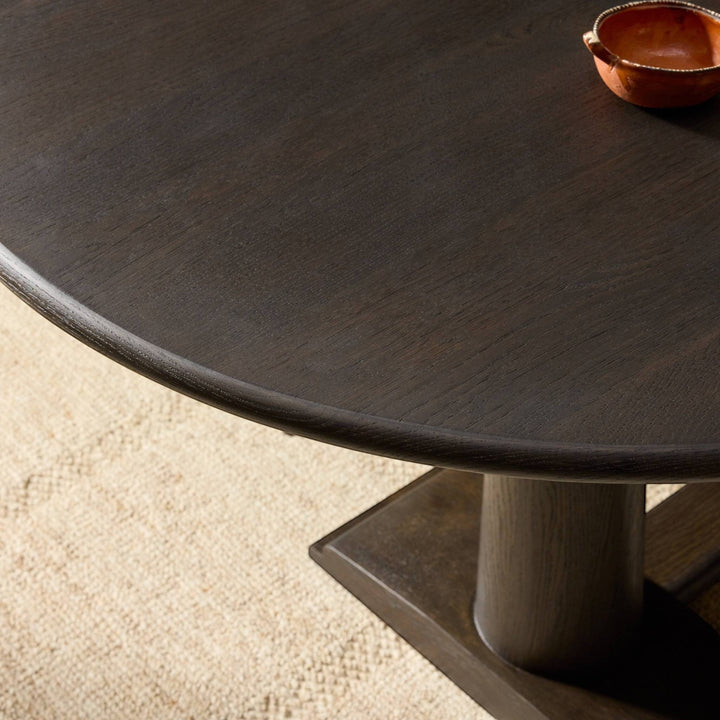Table à manger ovale en bois de chêne foncé Maison Olive avec piédestal central. Grain de bois subtil.