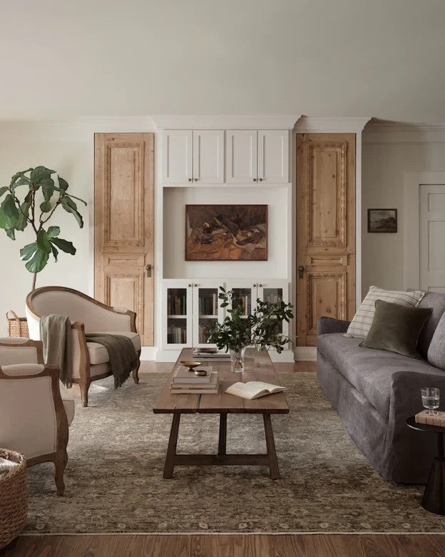 Tapis Maison Olive Junie Lagoon et naturel au motif antique dans un salon élégant avec mobilier en bois et canapé gris