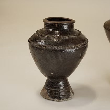 Vase Maison Olive en terre cuite brune émaillée avec détails gravés, style artisanal rustique sur pied.