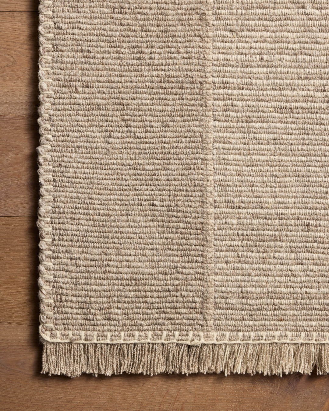 Détail de la texture et des franges du tapis Sigrid gris cendré et ivoire