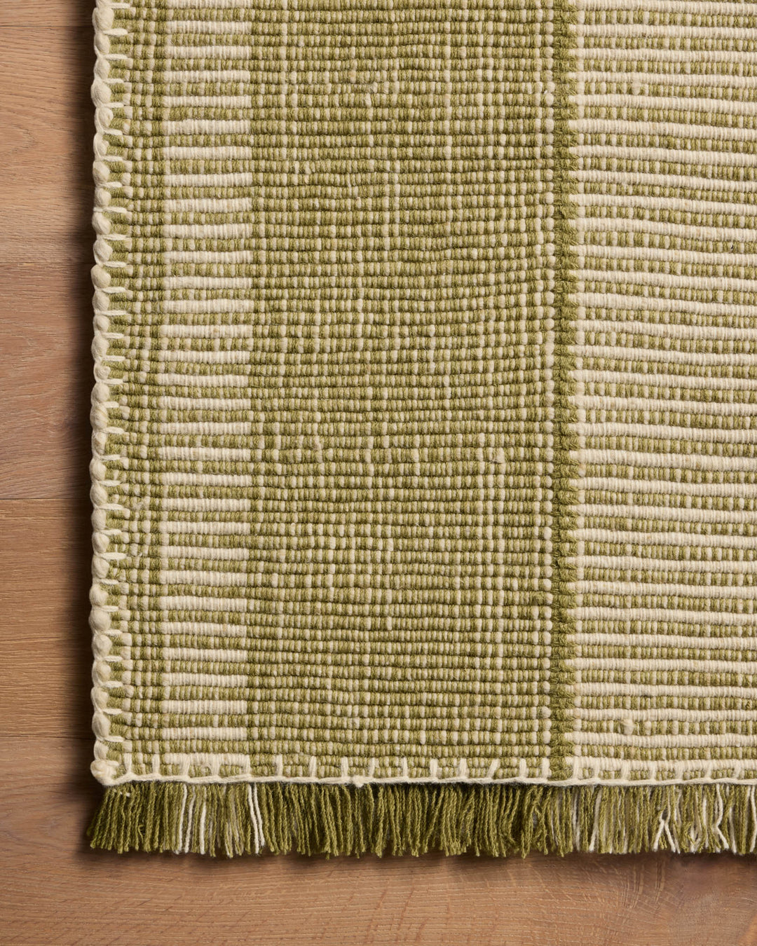 Détail de la texture et des franges du tapis Sigrid vert et ivoire